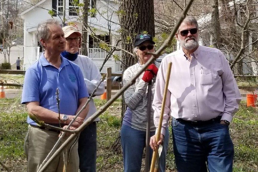 Volunteers standing with planting tools beside young trees