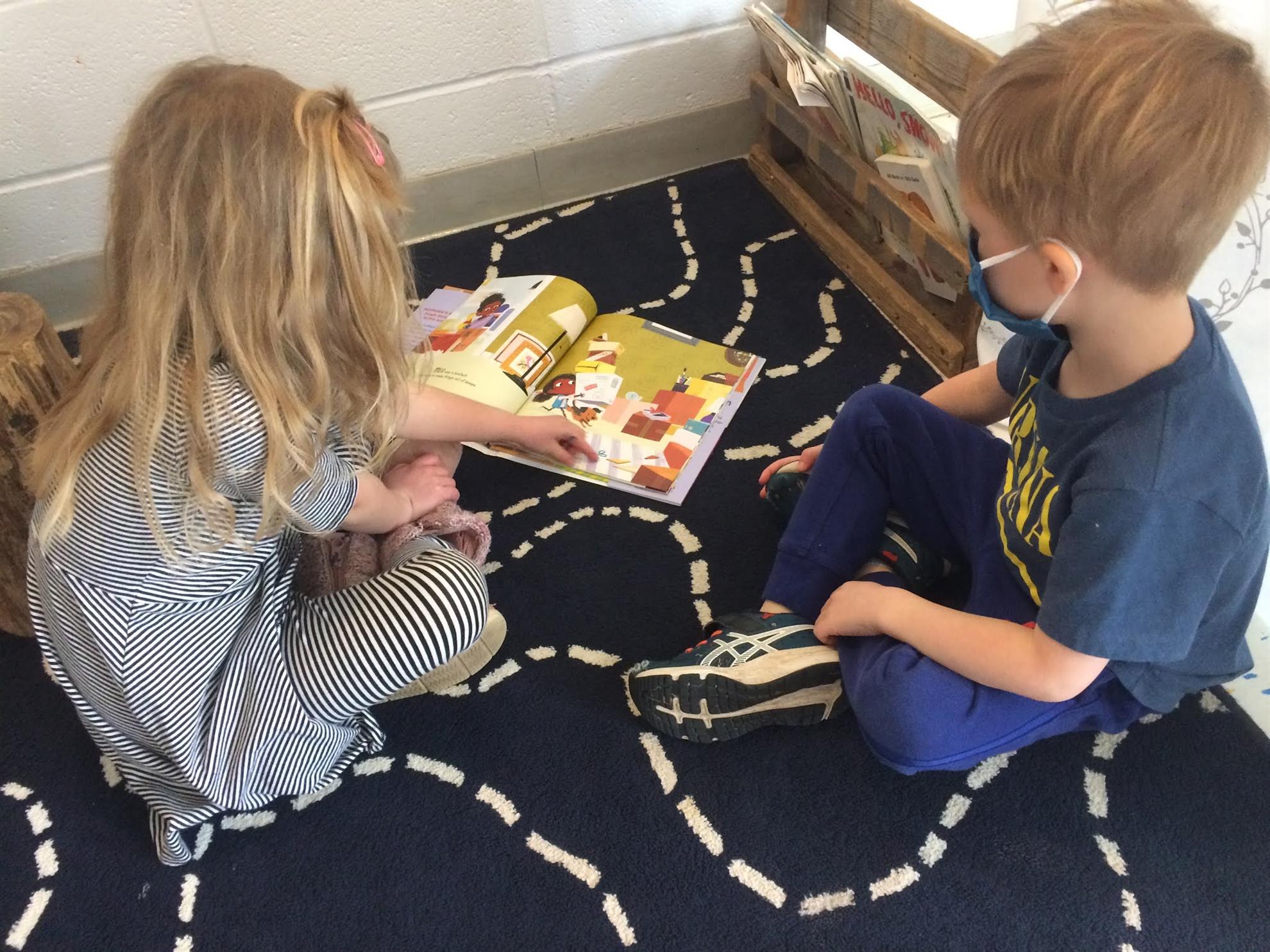 Two children reading a picture book indoors